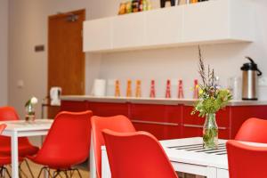 a restaurant with red chairs and a table with a vase of flowers at Hótel Heiðmörk in Reykjavík