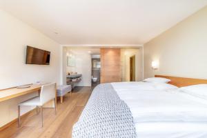 a hotel room with a large white bed and a desk at Hotel Allalin in Saas-Fee