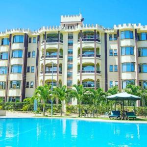 a hotel with a pool in front of it at Roma Stays - Splendid Kariba at Sunset Paradise Shanzu with a Swimming Pool in Mombasa