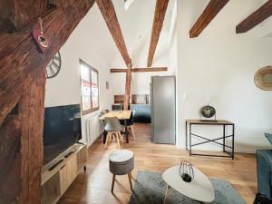 Una sala de estar con un televisor y una mesa. en Le Gite du Kaiser, en Kaysersberg