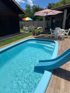ein blauer Pool mit Stühlen und einem Sonnenschirm in der Unterkunft Chalé Rústico com piscina in São Gabriel