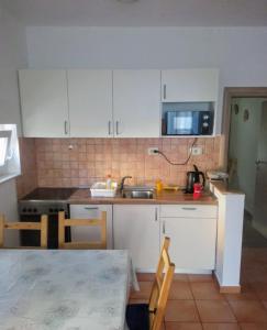a kitchen with white cabinets and a sink at Kod Male Gospe in Tribunj +10 photos