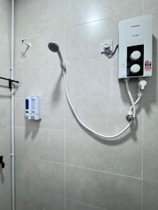 a shower with a hose attached to a wall at The Moment Homestay # WIFI TV Washer in Taiping