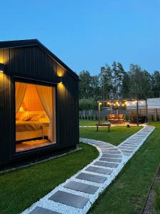 a black house with a stone walkway in the yard at Romantic Holiday House Nandi Rezidence Janupietis in Mellupi