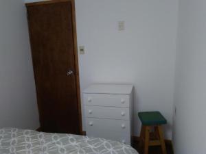 a bedroom with a bed and a stool next to a dresser at Charruas hostel in Montevideo