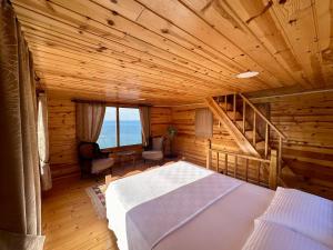 a bedroom in a log cabin with a bed and a staircase at NaylaKonak in Cayeli