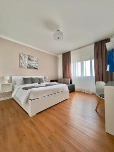 a white bedroom with a large white bed and wooden floors at Corso Venezia in Mestre