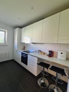 a kitchen with white cabinets and two bar stools at Soleil Rooms - Pure Living in the City Center in Hannover