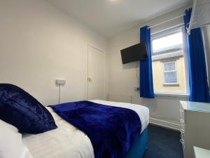 um quarto com uma cama com lençóis azuis e uma janela em The New Athena Hotel em Blackpool