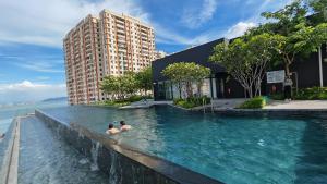 two people swimming in a swimming pool next to a building at Cityscape Haven - Explore George Town, Komtar & UNESCO in Jelutong