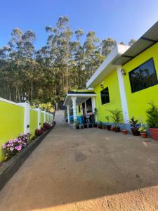 a yellow and white house with a driveway at Mountain cheers munnar in Munnar