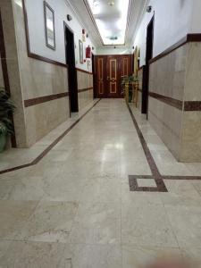 um corredor de um edifício com portas castanhas e piso em azulejo em روتانة للشقق المخدومة بالحمرا em Jeddah