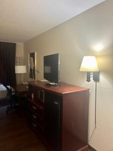 a room with a desk with a television on a dresser at Baymont by Wyndham Battle Creek/I-94 in Battle Creek