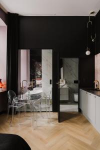 uma sala de jantar com uma mesa de vidro e uma cozinha em Apartament 10 by Hidden Garden em Lódź