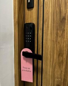 um fecho de porta com uma etiqueta rosa. em Apartament 10 by Hidden Garden em Lódź