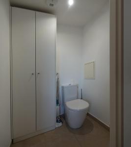 a white bathroom with a toilet and a cabinet at Appartement résidence neuve proche Versailles in Saint-Cyr-lʼÉcole
