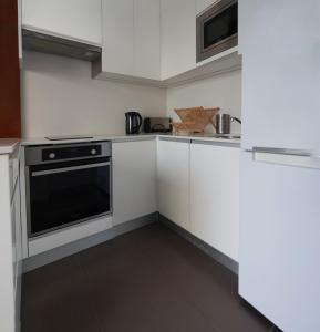 a kitchen with white cabinets and a black oven at Appartement résidence neuve proche Versailles in Saint-Cyr-lʼÉcole