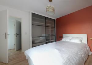 a bedroom with a white bed and a red wall at Appartement résidence neuve proche Versailles in Saint-Cyr-lʼÉcole