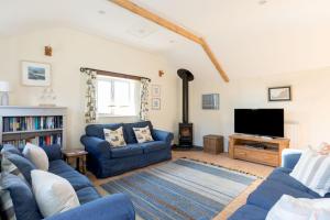 a living room with blue couches and a tv at The Barn, St Minver in Wadebridge
