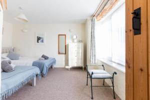 a bedroom with two beds and a chair and a window at The Barn, St Minver in Wadebridge