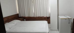 a bedroom with a white bed and a window at Pousada Gaby in Salgueiro