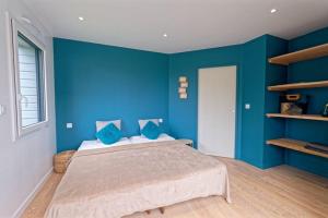 Schlafzimmer mit blauen Wänden und einem Bett mit blauen Kissen in der Unterkunft Ty Loum classé 4 étoiles in Ploubazlanec