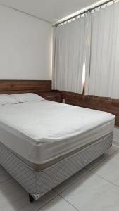 a white bed in a bedroom with a window at Pousada Gaby in Salgueiro