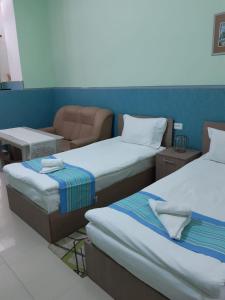 Habitación con 2 camas y una silla. en Lind Hotel and Guest House, en Gyumri