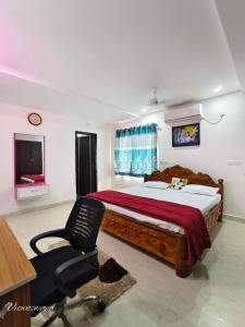 een slaapkamer met een bed, een stoel en een televisie bij Visweswara grand in Vijayawāda