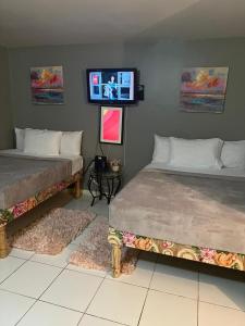 two beds in a room with a tv on the wall at Malibu Ocean View Studio in Montego Bay