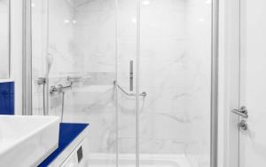 La salle de bains blanche est pourvue d'une douche et d'un lavabo. dans l'établissement Orbi City ApartHotel, à Batoumi