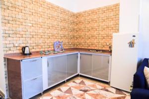 Villa Desert Rose في الأقصر: مطبخ مع خزانات حديد قابلة للصدأ وجدار من الطوب