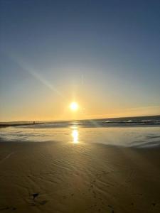 a sunset on a beach with the sun setting at Cwtch By The Sea in Porthcawl