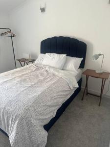 a bedroom with a large bed with a blue headboard at Cwtch By The Sea in Porthcawl