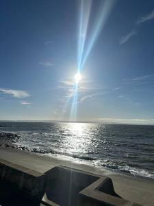 a sun shining over the ocean on a beach at Cwtch By The Sea in Porthcawl