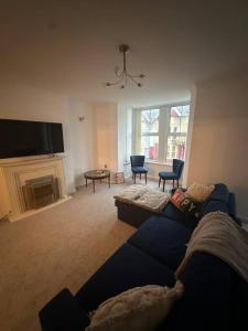 a living room with a blue couch and a fireplace at Cwtch By The Sea in Porthcawl