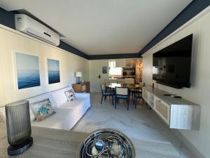 een woonkamer met een bank en een televisie bij Flat+deck ao lado da igrejinha in Praia dos Carneiros