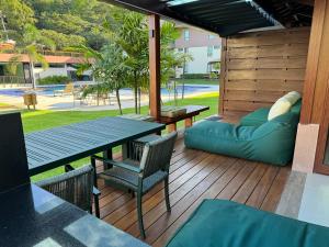 een terras met een tafel en stoelen en een bank bij Flat+deck ao lado da igrejinha in Praia dos Carneiros