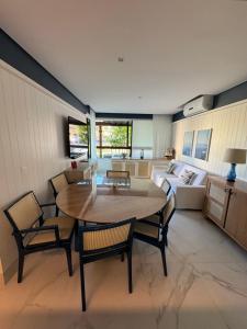 a living room with a table and chairs and a couch at Flat+deck ao lado da igrejinha in Praia dos Carneiros