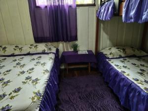 Cette petite chambre comprend deux lits et une table. dans l'établissement Pensión y Cabinas Colibrí B&B Costa Rica, à Monteverde Costa Rica