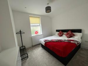 a bedroom with a bed with red pillows on it at Lovely 4-Bed House in Central Wolverhampton in Wolverhampton