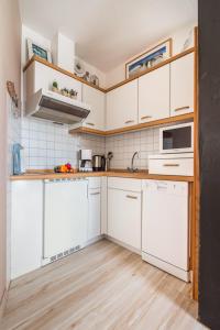 a kitchen with white cabinets and wooden floors at Seepferdchen in der Villa Medici in Norderney