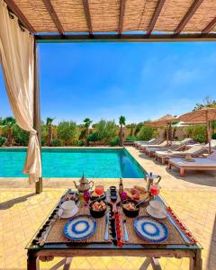a table with food on it next to a swimming pool at Al Destino Villa Riad Spa Luxury Marrakech in Marrakech