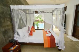 ネゴンボにあるOlanro Hotel Negomboのベッドルーム(白いカーテン付きの天蓋付きベッド1台付)