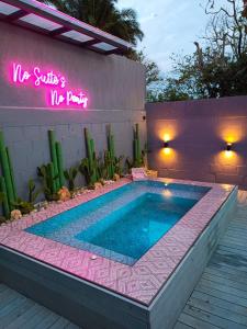 a swimming pool in front of a building with a neon sign at Hotel Suites Lounge La Viga in Cali