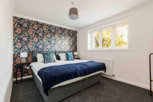 um quarto com uma cama com lençóis azuis e papel de parede floral em 2 bedroom House-Driveway - Bournemouth Hospital - Long Stay Discounts - Lima Apartments Ltd em Bournemouth