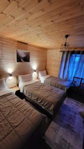 three beds in a room with wooden walls and ceilings at Bujtina Pllumi Theth in Theth