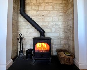 einen Holzofen in einer Ziegelwand in der Unterkunft Cosy Cotswold Home - Jacobs Cottage in Cirencester + 33 Fotos