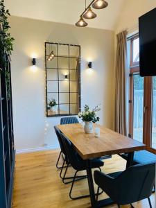 a dining room with a wooden table and chairs at Stylish contemporary seaside holiday home with 5 bedrooms, sea view, parking and EV point in Kent