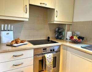 een keuken met witte kasten en een fornuis met oven bij Cosy Cotswold Home - Jacobs Cottage in Cirencester